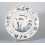 An 18th century English delft plate with landscape centre and insect and flower border, 9" dia (