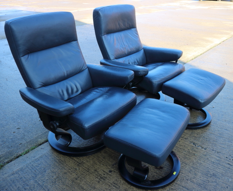 A pair of "Stressless" grey leather armchairs and matching stools, on circular bases