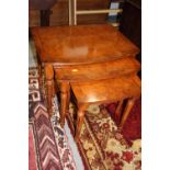 A nest of three figured walnut and banded bowfront occasional tables, 23 1/2" wide