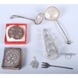 A book of common prayer with embossed silver cover, a pair of white metal sugar tongs, formed from