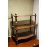 A mahogany serpentine three-tier whatnot, on turned supports, 24" wide