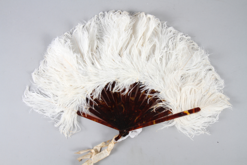 An early 20th century white ostrich feather fan with faux tortoiseshell sticks and guards, 10" long