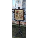 A Victorian carved rosewood pole screen with needlework panel, on tripod splay supports