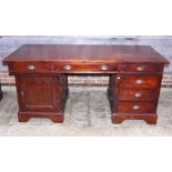 A teak/hardwood double pedestal desk, fitted six drawers and cupboard, on bracket feet, top 31" x