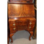 A figured walnut fall front bureau of early 18th century design, fitted slide over two drawers, on