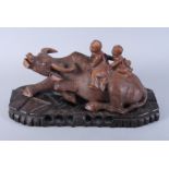 An early 20th century Chinese carved hardwood water buffalo with two children on its back, on