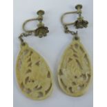 A pair of carved bone earrings depicting