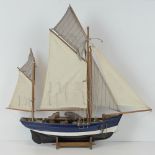 A contemporary scale model fishing skiff, complete with deck furniture, sails and stand,