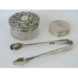 A pair of HM silver sugar tongs and a cut glass vanity pot with HM silver repoussé lid,