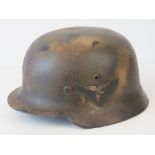 A WWII German Luftwaffe helmet, later camo painted having applied decal,