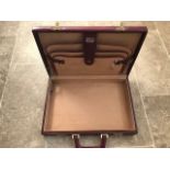 A fine burgundy leather brief case with brass fittings and swing handle opening to reveal