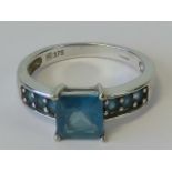 A 9ct white gold and topaz ring, central square cut blue topaz approx 1ct,