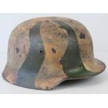 A WWII German helmet, later textured winter camo painted, leather lining and chin strap.