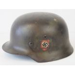 A WWII German helmet, later camo painted having applied double decal, leather lining and chin strap.