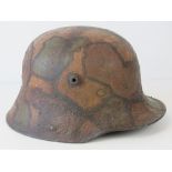 A WWI German M16 helmet, later camo painted, leather lining and chin strap.