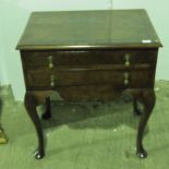 An early 19th century quarter veneered waltut two drawer lowboy raised over shaped legs.