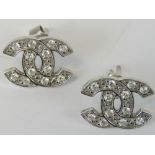 A pair of interlocking C design earrings, white metal encrusted with white stones,