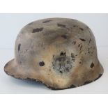 A WWII German helmet, later snow camo painted having applied decal, leather lining and chin strap.