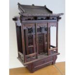 A Chinese devotional carved hardwood shrine having central small door within a large ornately