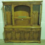 A contemporary yew wood dresser base with drawers and doors having twin glazed doors arch top