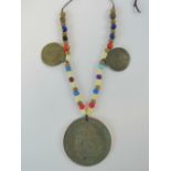 A reproduction Indian Peace medal on necklace with beads.