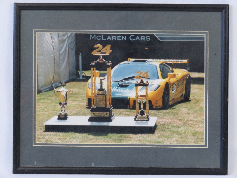 A coloured photograph of a McLaren F1GTR 'Harrods', signed verso by Derek Bell,