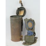 A WWII German Army gas mask, complete with filter, and spare lenses to top of lid.