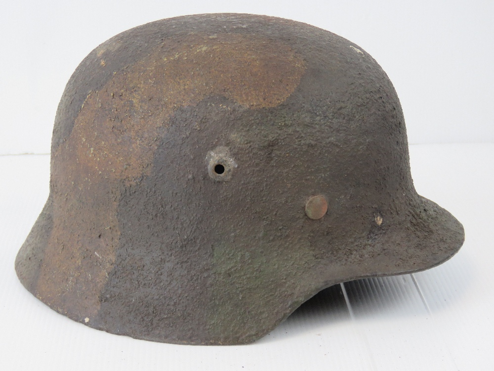 A WWII German M40 camo helmet with original liner and chin strap.