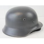 A reproduction German M43 steel helmet with liner and chin strap, painted grey.