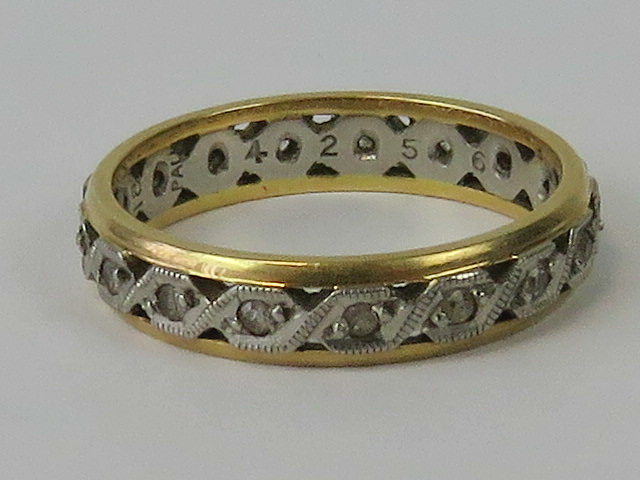 An 18ct gold and platinum eternity ring, central platinum band set with white stones,