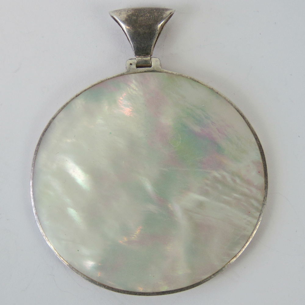 A silver and mother of pearl pendant, large oval disk of mother of pearl, 5.
