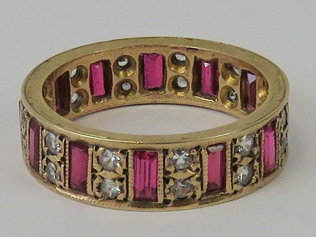 A 9ct gold eternity ring set with baguette cut red stoned and pairs of white round cut stones,