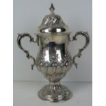 A large HM silver lidded trophy, repoussé body and lid, single foot and twin handles,