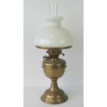 An Edwardian brass oil lamp complete with milk glass globe and chimney, standing 53cm high.