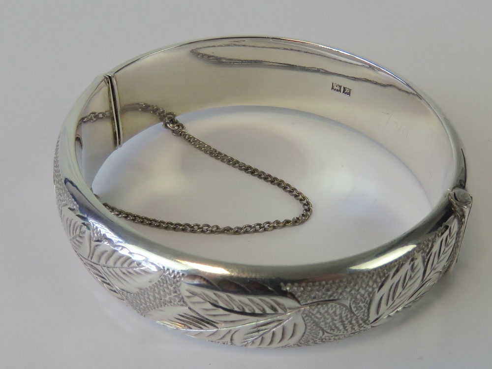 A HM silver bangle with engraved leaf pattern to front, complete with guard chain,