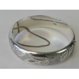 A HM silver bangle with engraved leaf pattern to front, complete with guard chain,