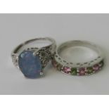 Two silver rings; one half eternity set with alternating pink and green stones,