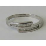 A silver crossover ring set with baguette cut white stones, stamped 925, size T.