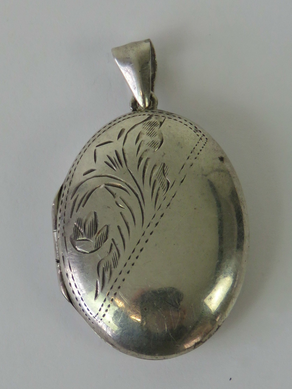 A silver locket of oval form with floral engraving to front, stamped 925, 4.5cm including bale.