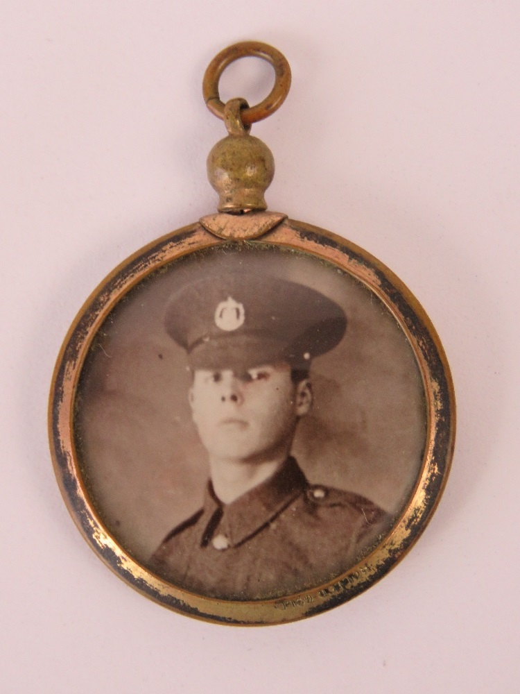 A rolled gold locket containing a photo of a man in uniform.