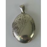 A silver locket of oval form with floral