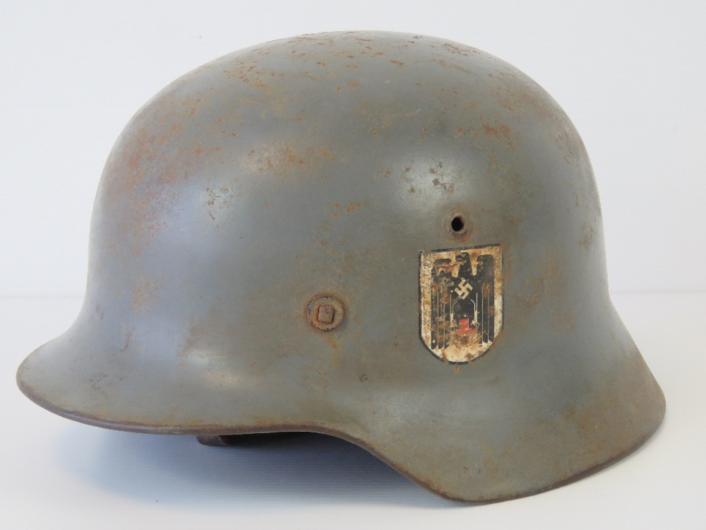 A WWII German helmet with double decal, handwritten name within, replacement liner and chin strap,