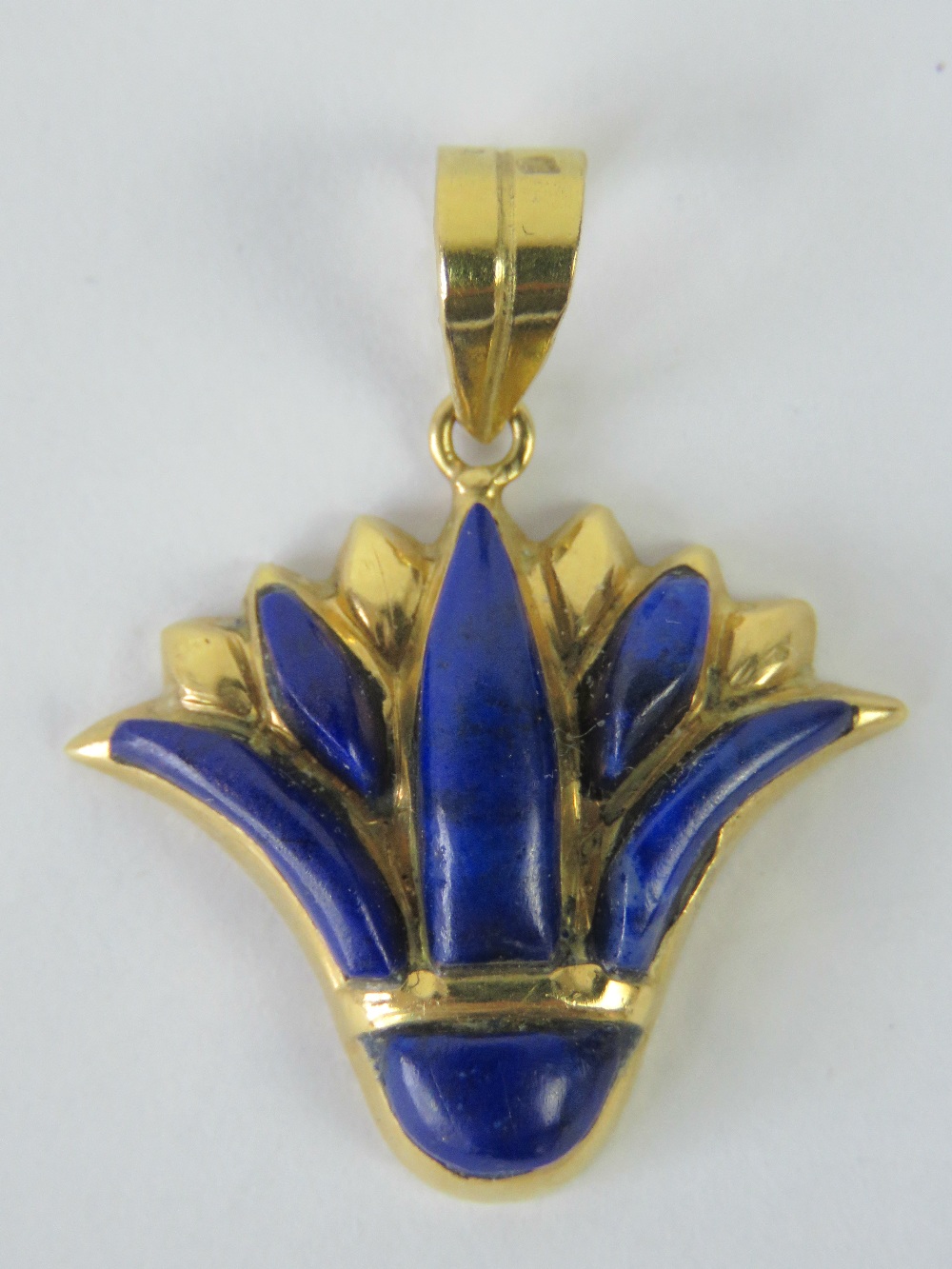 A yellow metal and lapis lazuli pendant having single Arabic hallmark upon,