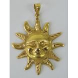 A yellow metal pendant in the form of the sun having face upon, single Arabic hallmark, 5.