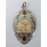 An unusual silver pendant having carved bone cat and two cabachon stones upon,