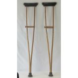 A pair of vintage adjustable crutches in ash, each with leatherette arm support and rubber ferrule.