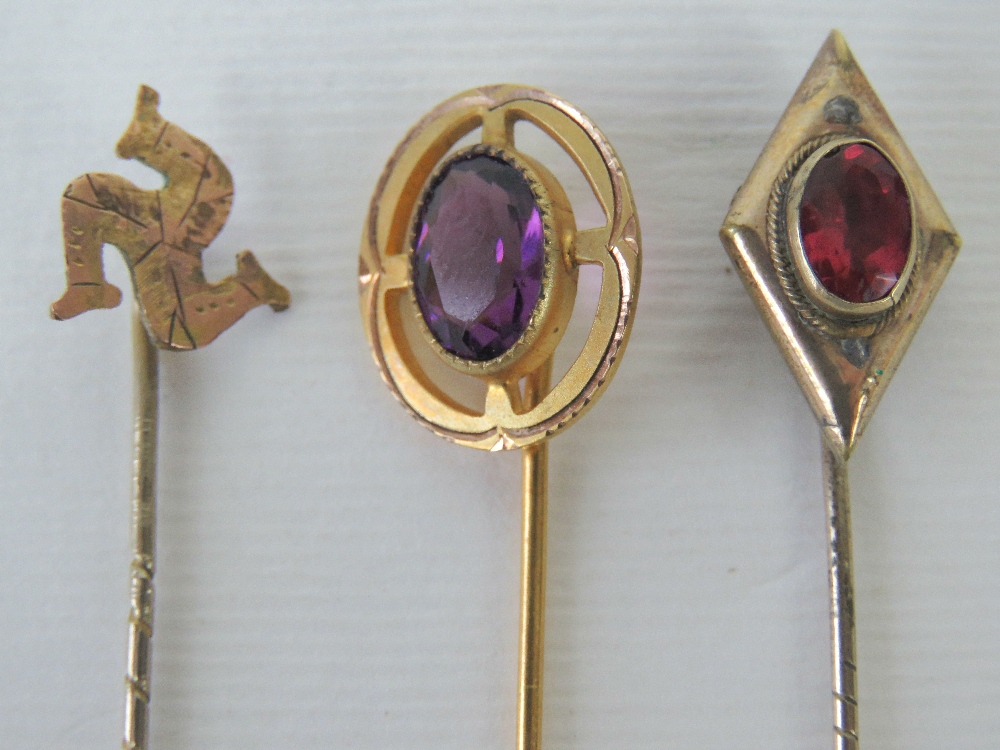 Three yellow metal tie pins, one of diamond form set with large oval pink stone,