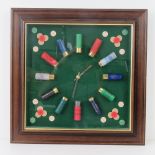 A framed clock made from twelve spent shotgun cartridges complete with caps, 32 x 32cm.