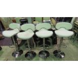 A set of four contemporary rise and fall white leatherette bar stools.