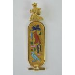 A yellow metal cartouche pendant with enameled hieroglyphics upon,